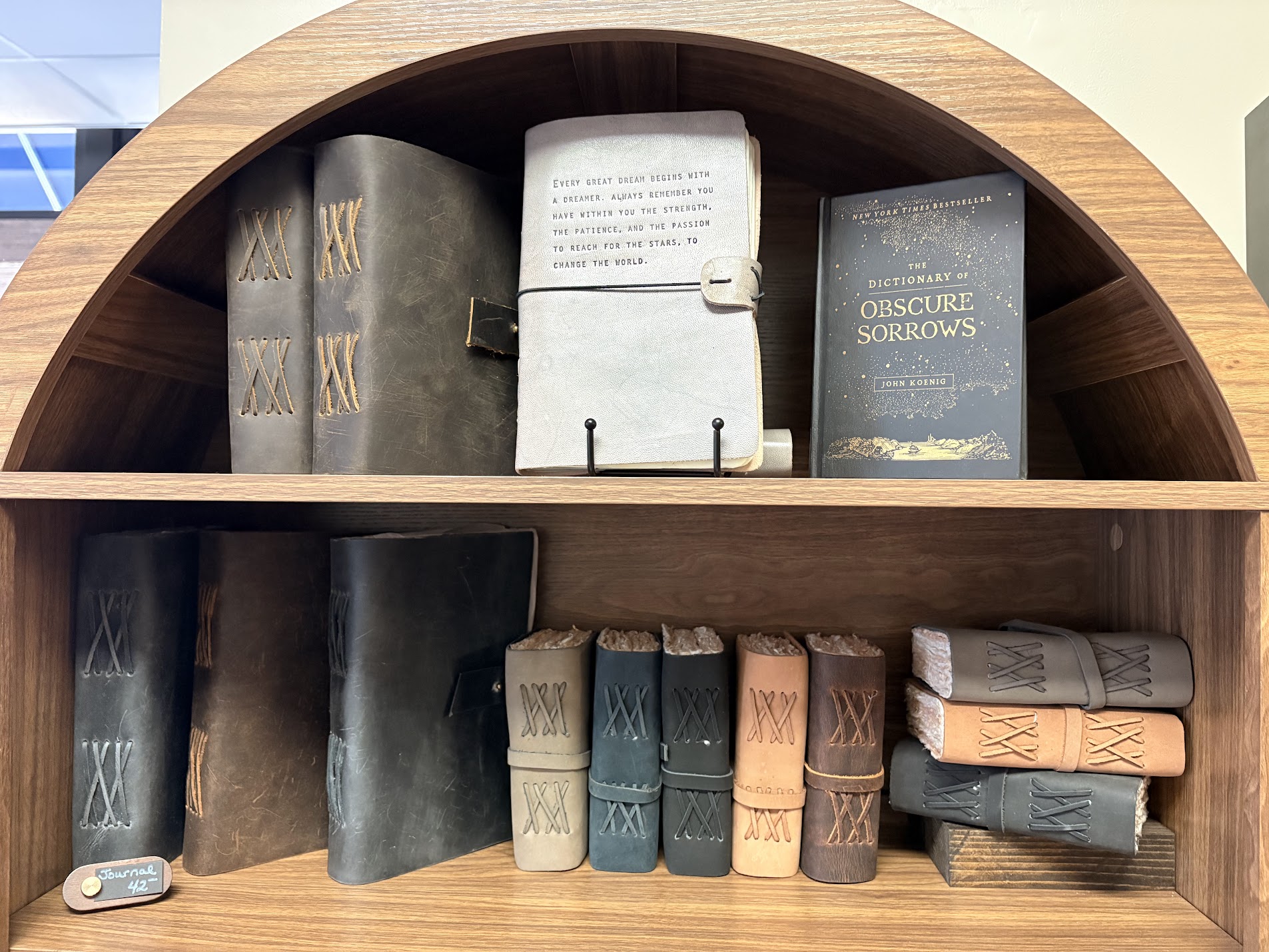 Journals and small books displayed in an arched wooden shelf.