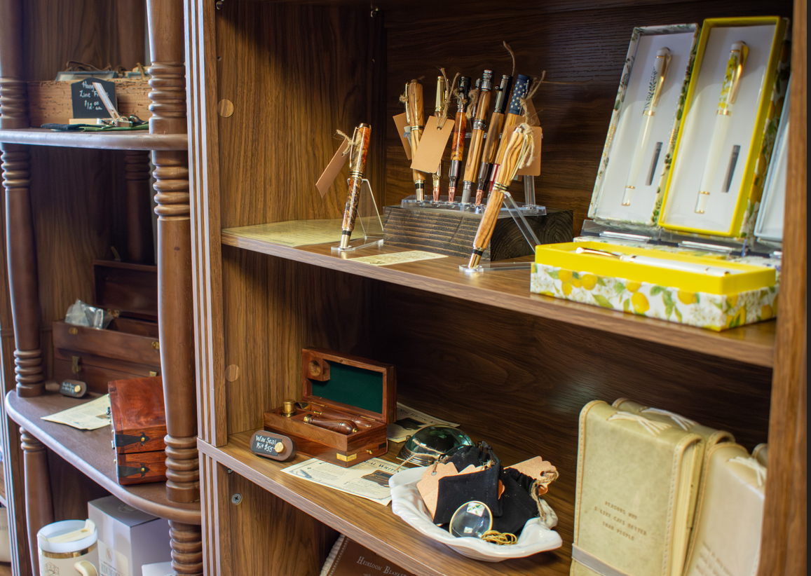 Pens, boxed stationery, and small gifts arranged on wooden shelves.